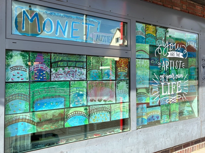 Fensterfront von ILKAs Malschule, versehen  mit vielen Kunstwerken der Teilnehmer.